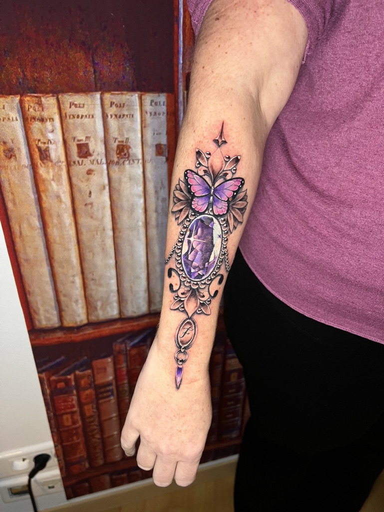 Tattoo-Bijoux avec un papillon rose et violet, une pierre Améthyste à facettes violettes en forme ovale et un pendentif avec une initiale