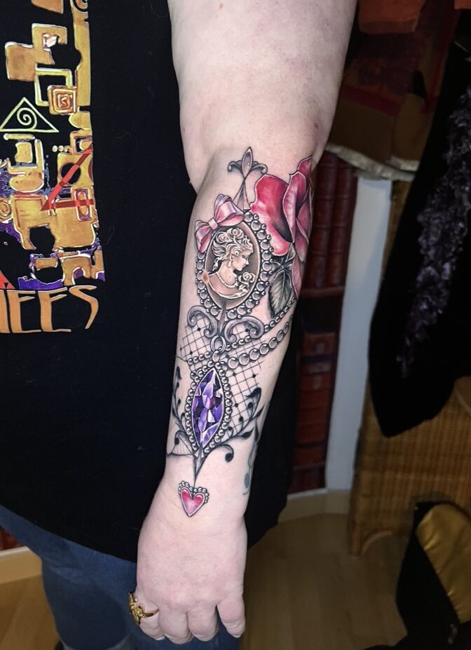 Tattoo-Bijoux avec un camée, un noeud en soie rose, une rose réaliste dans les teintes roses foncés, une pierre améthyste à facettes violettes en forme de marquise et de la dentelle