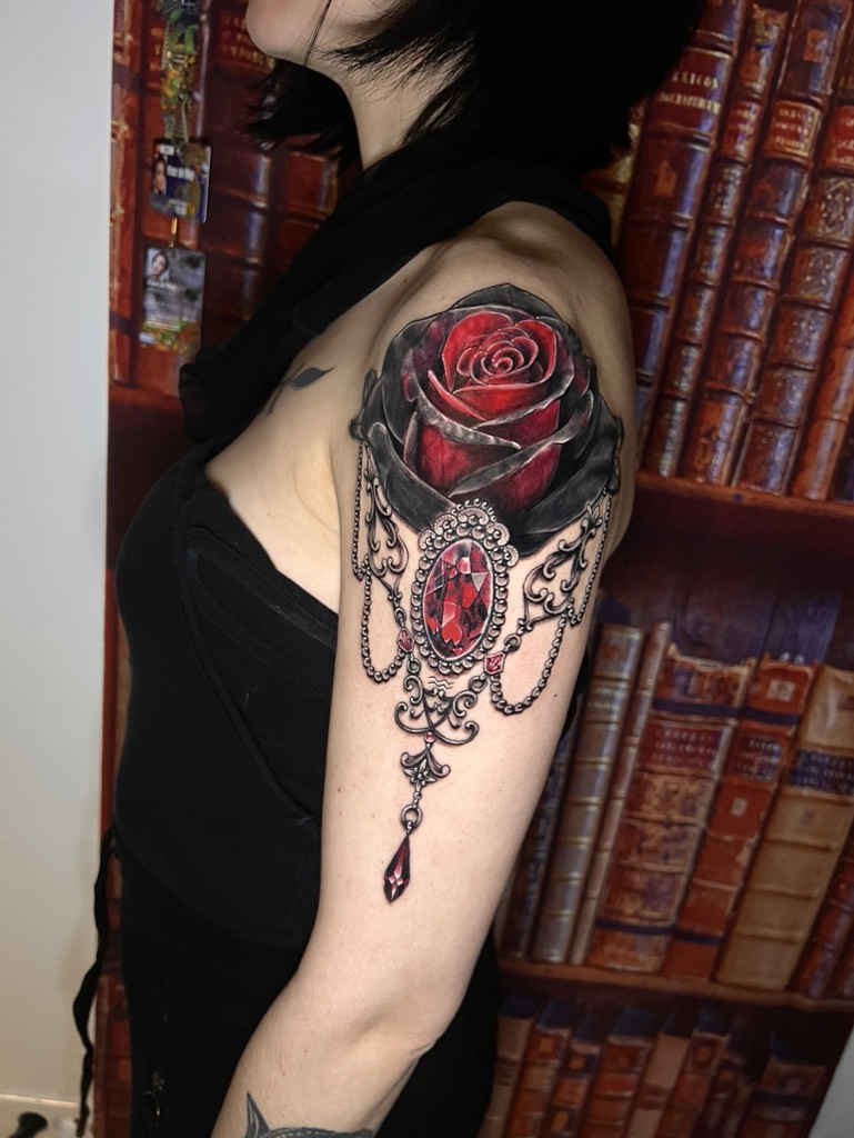 Tattoo-Bijoux avec une rose réaliste rouge et noire, une pierre rubis à facettes rouges en forme ovale et des ornements bijoux