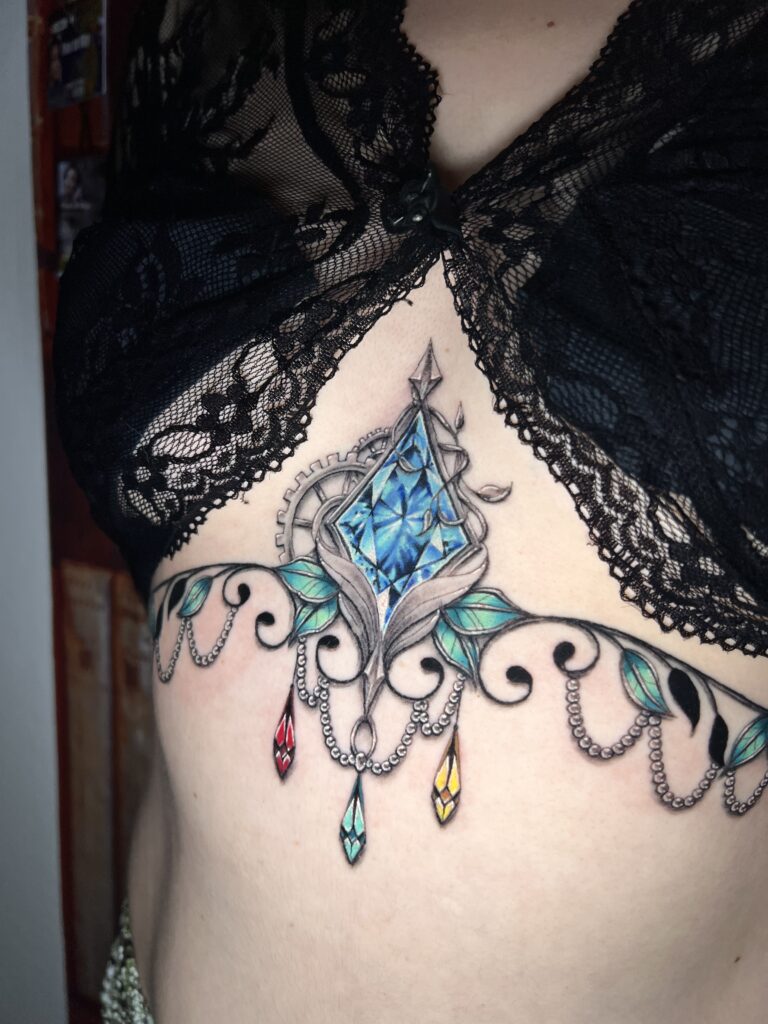 Tattoo-Bijoux avec des rouages mécaniques steampunk, des feuilles et lianes, et une pierre à facettes bleues en forme de losange