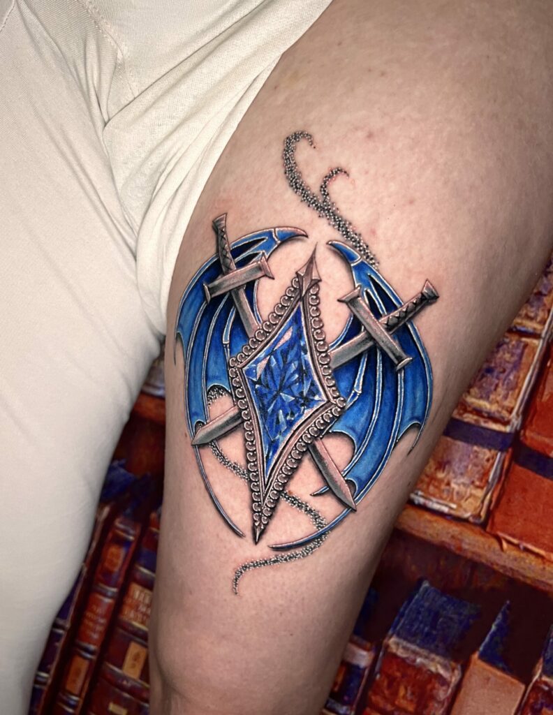 Tattoo-Bijoux avec une paire d'ailes de dragon bleues, deux épées, une pierre à facettes bleues en forme de losange et des paillettes